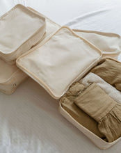 Load image into Gallery viewer, A set of four organic cotton travel packing cubes sitting on a bed, perfect for organising and storing travel essentials while being eco-friendly.