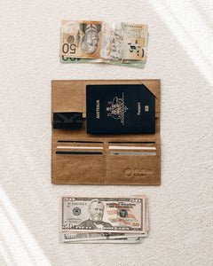 Northern Olive Travel Wallet in brown holding passport and cards  with  AUD and USD beside the wallet. 
