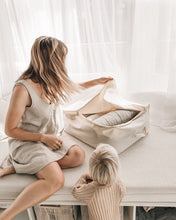 Load image into Gallery viewer, Beige organic cotton storage bag being packed by mother and child 
